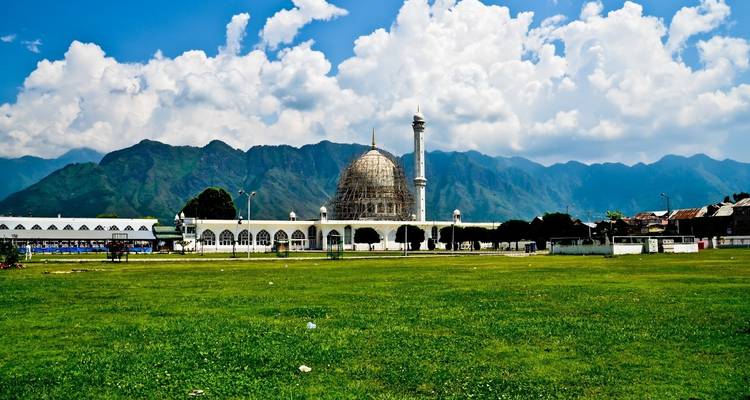 Weiße Moschee mit Bergen im Hintergrund.