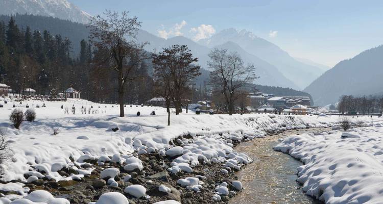 Verschneite Landschaft mit einem Fluss und Bergen.