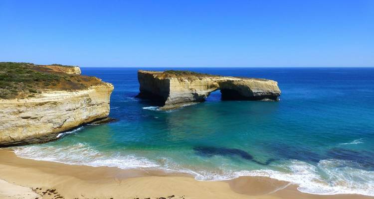 Côte rocheuse avec une arche naturelle et des eaux turquoise.