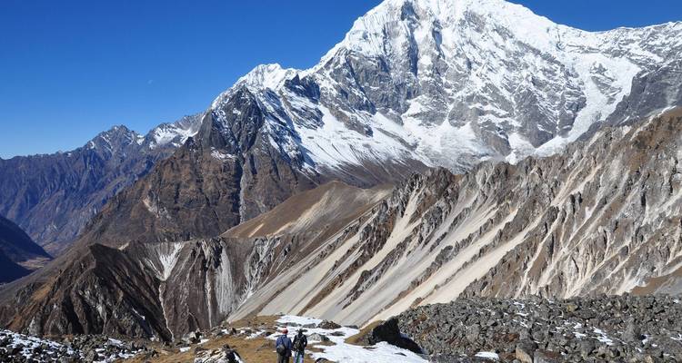 Dos personas caminando por montañas nevadas.