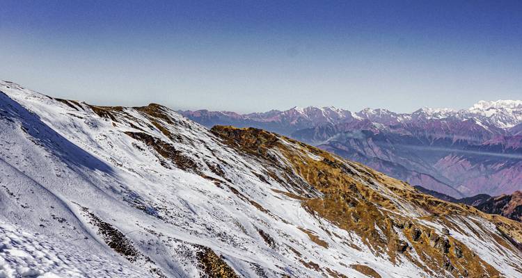 Pente de montagne enneigée avec chaîne de montagnes panoramique.