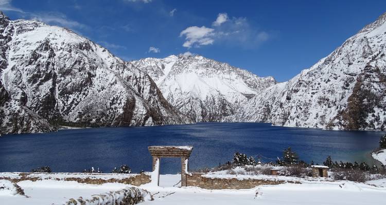 Schneebedeckte Berge, die einen blauen See unter klarem Himmel einrahmen.