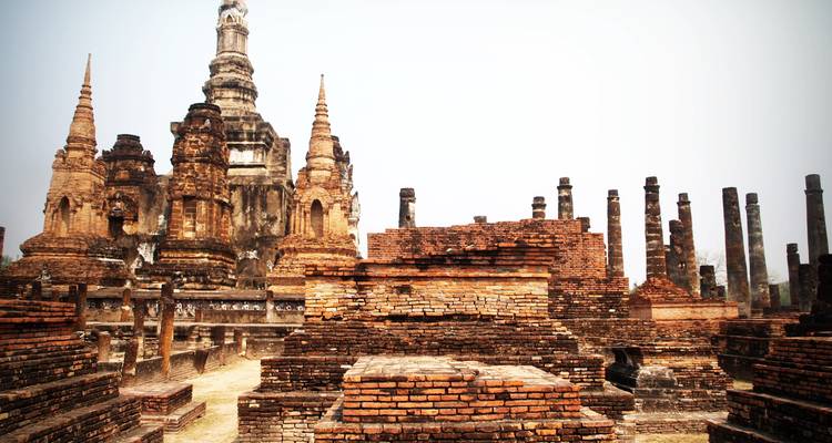 Ancient brick stupas and weathered pillars of Sukhothai Historical Park.