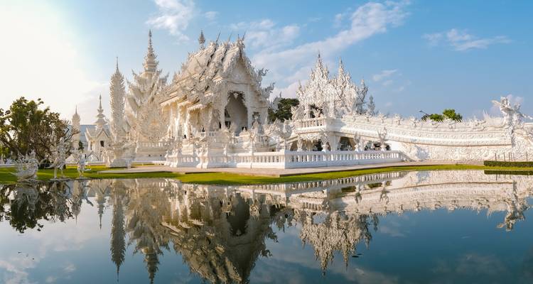 Dazzling white temple reflected perfectly in a tranquil ornamental pond.