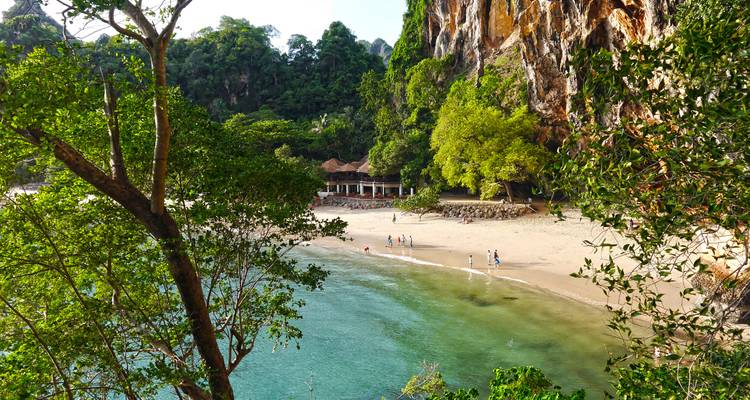 Secluded sandy cove bordered by jungle-clad cliffs and turquoise sea.