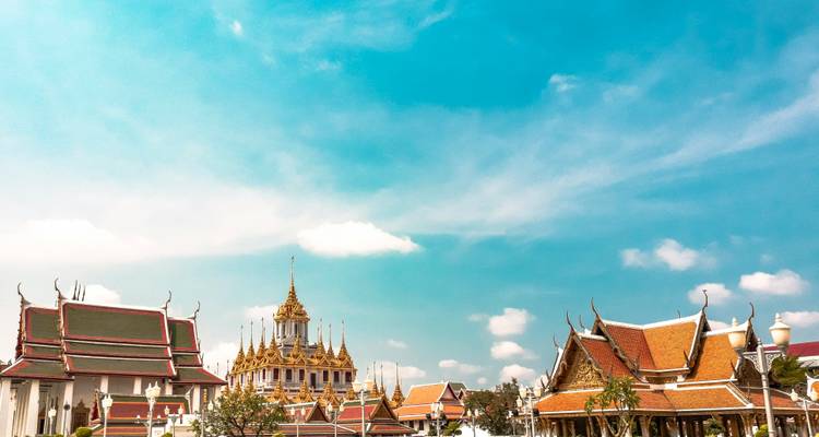 Golden spired temples and red-tiled roofs contrast against a bright turquoise sky.