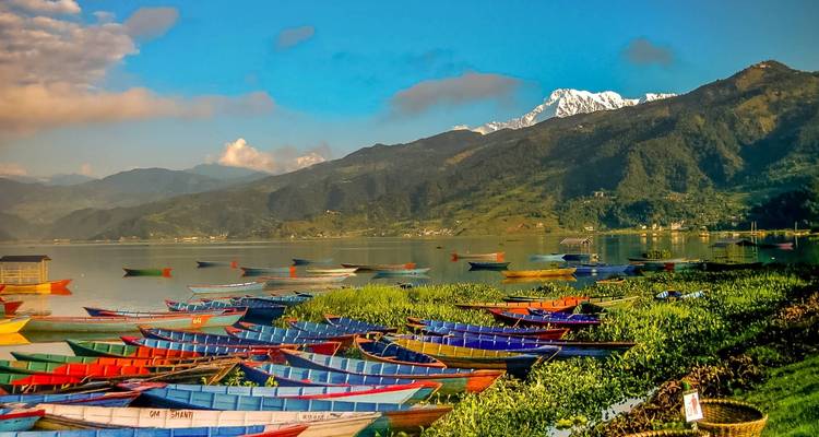 Ruderboote auf einem See mit Bergen im Hintergrund in Pokhara, Nepal.