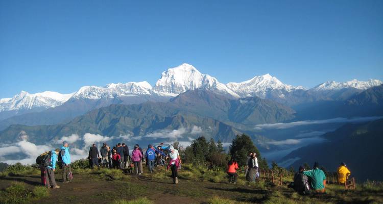 Groep toeristen die uitkijkt over een panoramisch berglandschap.