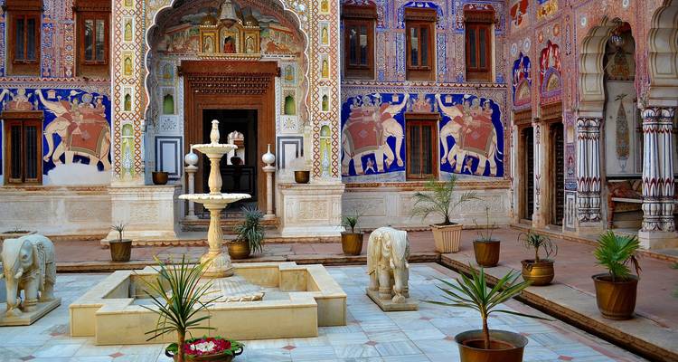 Cour avec une fontaine et des peintures murales détaillées.