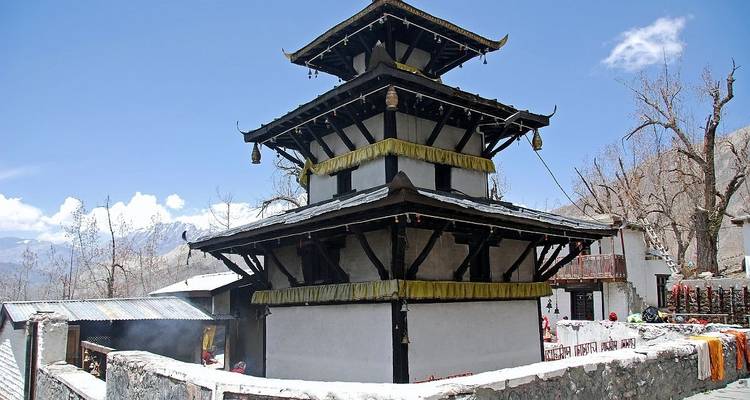 Pagoda-style temple surrounded by barren land with a mountain backdrop.