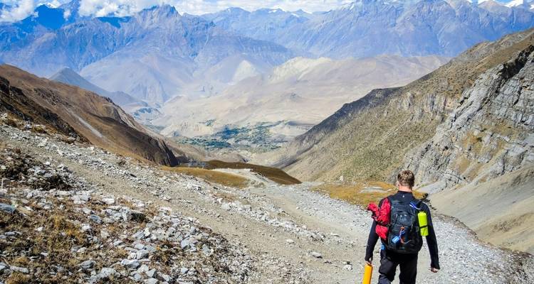 Hiker descending a mountain trail with expansive view.