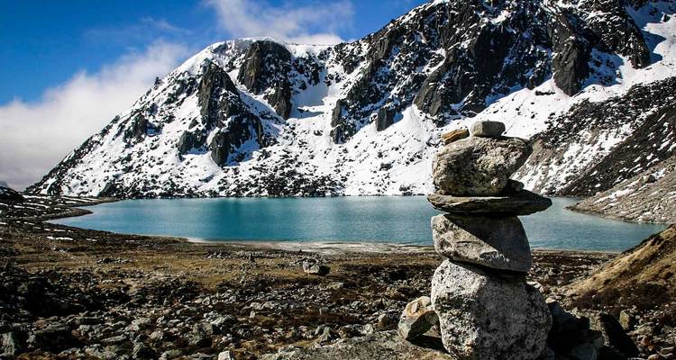 Felsige Landschaft mit einem schneebedeckten Berg an einem See.