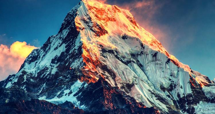 Schneebedeckter Berggipfel, beleuchtet von goldenem Licht.