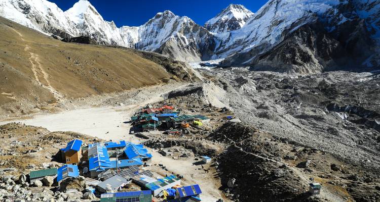Ein abgelegenes Bergdorf mit hohen schneebedeckten Gipfeln in der Ferne.