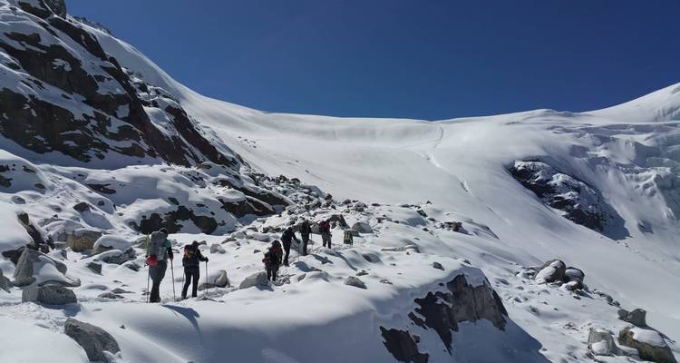 Group of hikers walking through a snowy mountainous area.