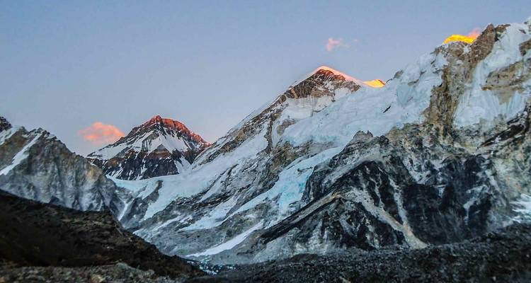 Mountains at sunrise with peaks lit by orange light.