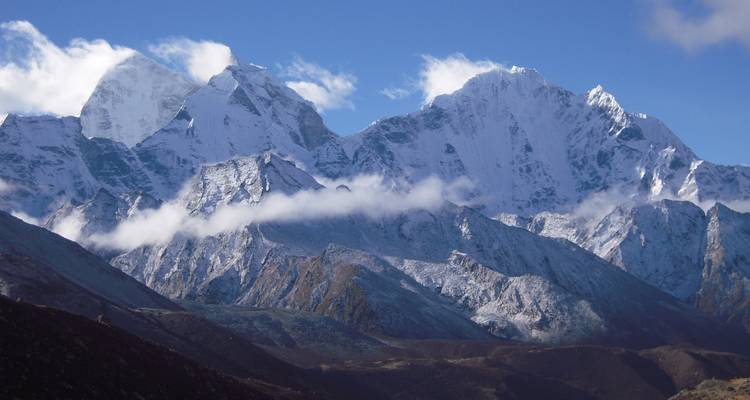 A mountain range with snow-capped peaks against a blue sky.