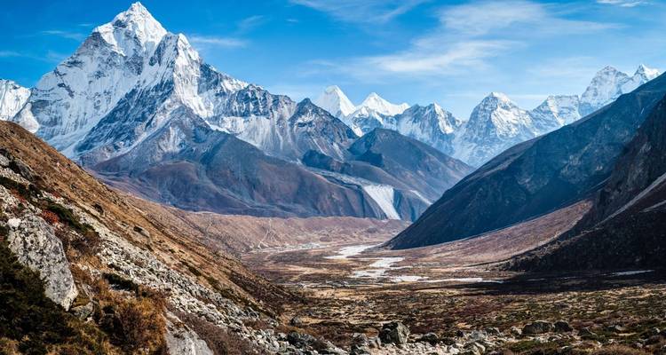 A breathtaking view of a valley surrounded by towering snowy peaks.