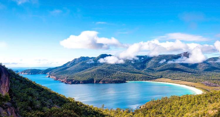 Vue panoramique des chaînes de montagnes et du littoral sous un ciel bleu éclatant.