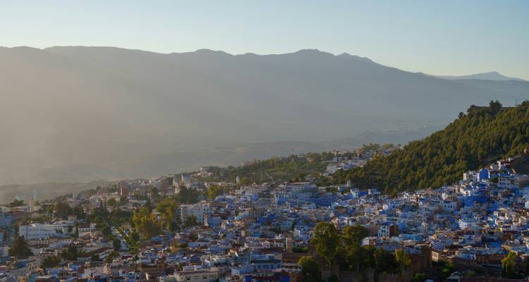 Vue panoramique de la médina peinte en bleu de Chefchaouen nichée sous les montagnes brumeuses à l'aube.