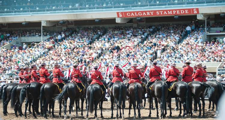 Policía Montada Real Canadiense a caballo en uniforme de gala formados frente a las gradas llenas en la Estampida de Calgary.