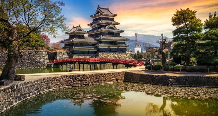 Château de Matsumoto avec un pont rouge et la verdure environnante.