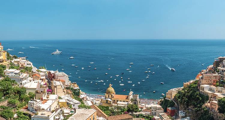 Panoramic view over colourful Positano cascading down cliffs to the bright blue Tyrrhenian Sea.