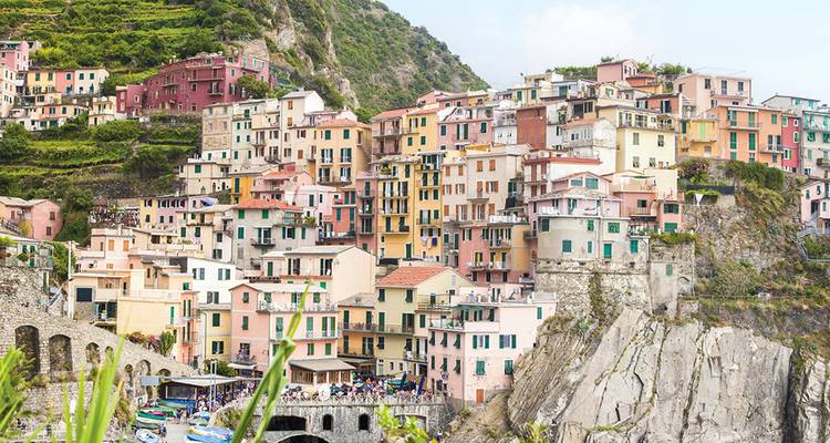 Las coloridas casas del acantilado de Manarola descienden en cascada hacia el mar de Liguria entre viñedos escalonados.