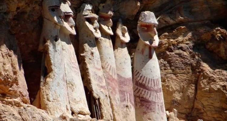 Antike Statuen, die an einer Felswand aufgereiht stehen.