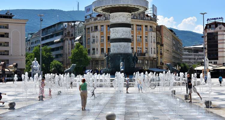 Place de ville animée avec des fontaines et des gens qui profitent de l'endroit.