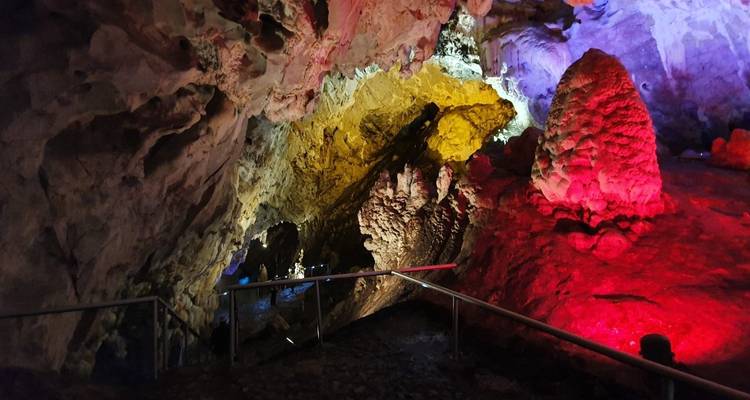 Intérieur d'une grotte aux éclairages colorés avec des formations de stalactites.