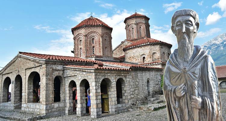 Église en pierre avec des arches et une statue devant.