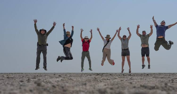Groupe de personnes sautant dans un paysage désertique.