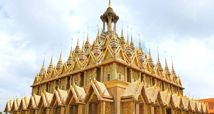 Funkelnder goldener Tempel mit verzierten Türmen unter einem bewölkten Himmel.