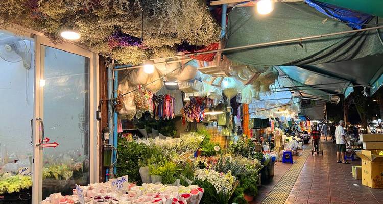 Puesto del mercado de flores cubierto con flores secas colgadas y cubetas de ramos frescos por la noche.