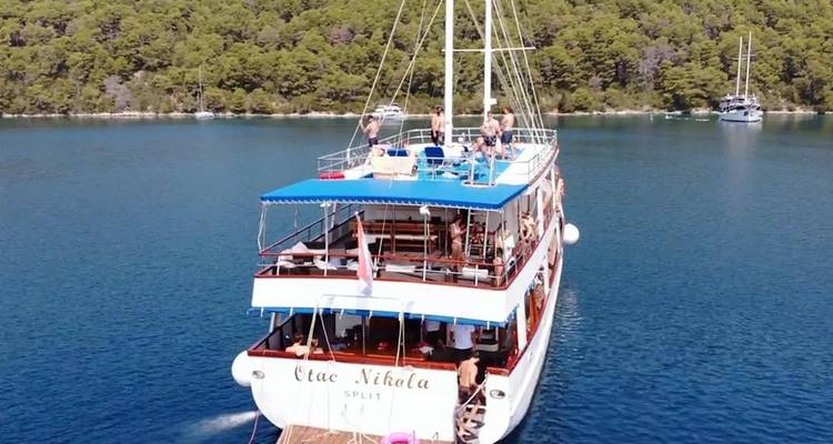 Ein Boot mit Menschen an Bord, das durch ruhige Gewässer fährt, umgeben von üppigen Landschaften.