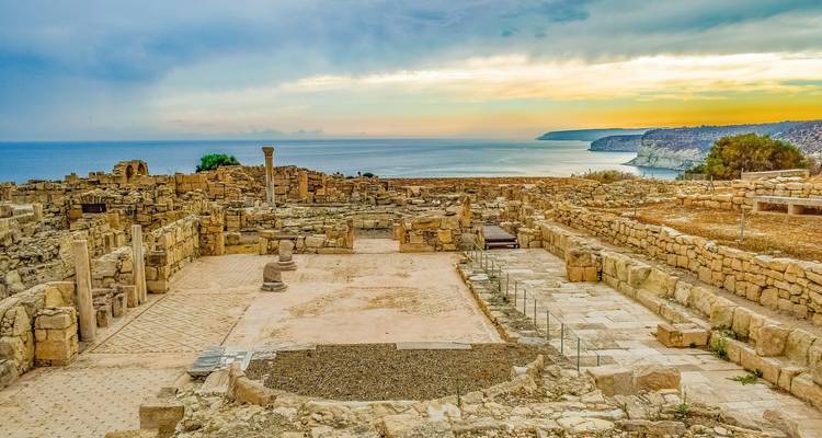 Ancient ruins overlooking the sea with a cloudy sky.