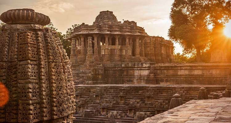 Temple de pierre aux sculptures complexes dans une lumière dorée de coucher de soleil.