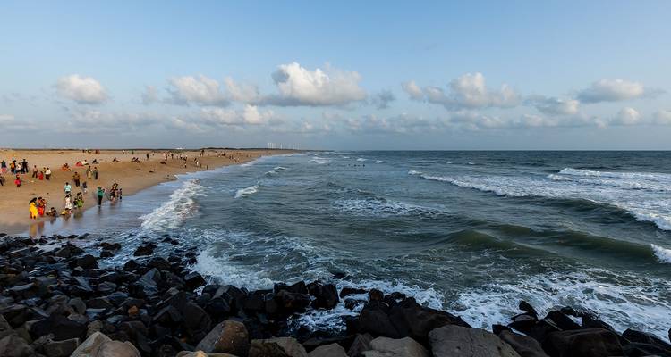 Strand met een menigte die geniet van de golven.