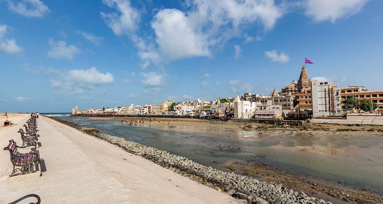 Kuststad uitzicht met een lange promenade en prominente tempel.