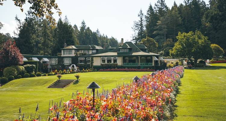 Beautiful garden with a flower-lined walkway in front of a large house.