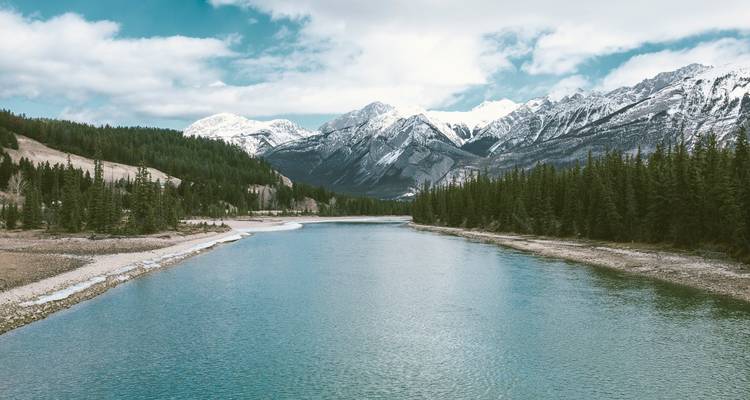 Serene river with snowy mountains in the background.