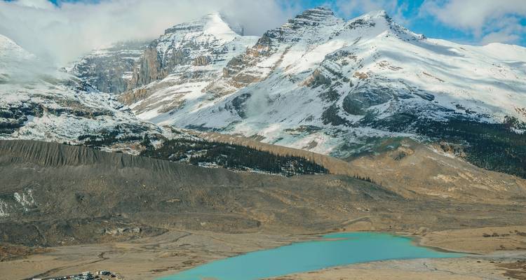 Mountain range with a glacier-fed lake and snow-capped peaks.