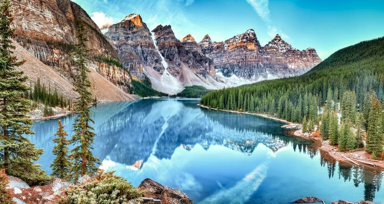 A stunning view of a pristine lake surrounded by majestic mountains and dense forests.