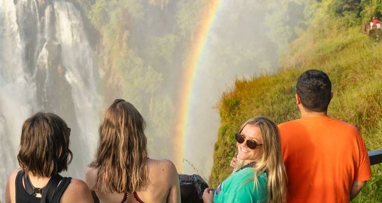 Les voyageurs admirent un arc-en-ciel éclatant qui jaillit de la brume des chutes Victoria.