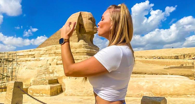 Tourist spielt verspielt mit der Sphinx.
Wait, let me provide a better translation:
Tourist posiert spielerisch mit der Sphinx.