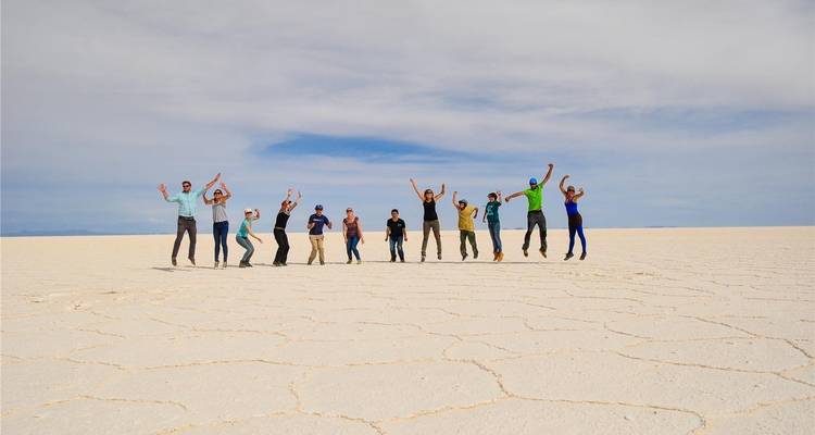 Energische Gruppe von Reisenden, die gleichzeitig auf der riesigen weißen Fläche des Salar de Uyuni in die Luft springen