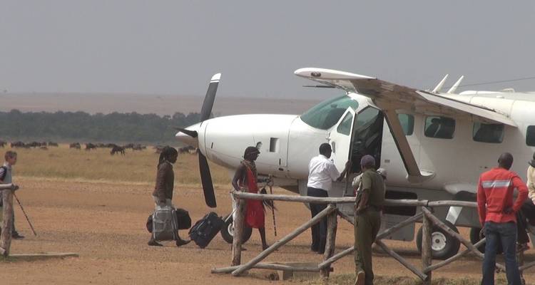 Mensen die zich voorbereiden om aan boord te gaan van een klein vliegtuig op een onverharde landingsbaan.