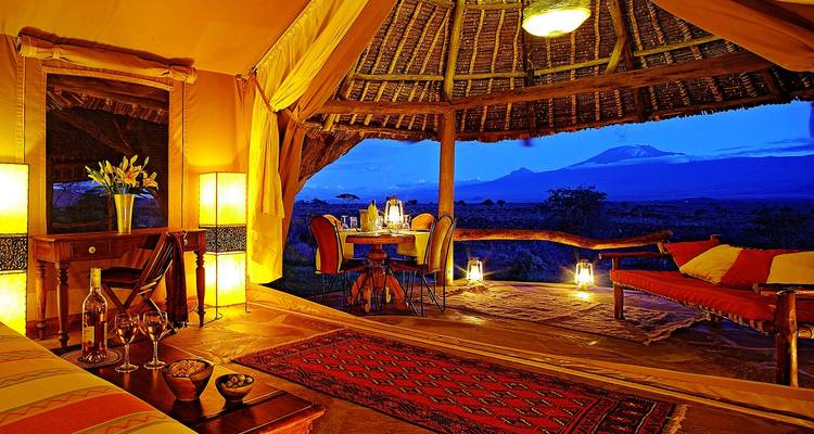 Luxueus tentinterieur met uitzicht op een berg en avondlucht.