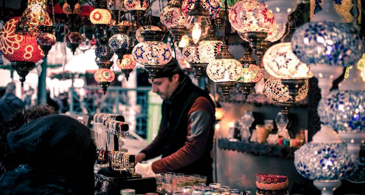 Marktstand mit bunten hängenden Lampen und einem Verkäufer